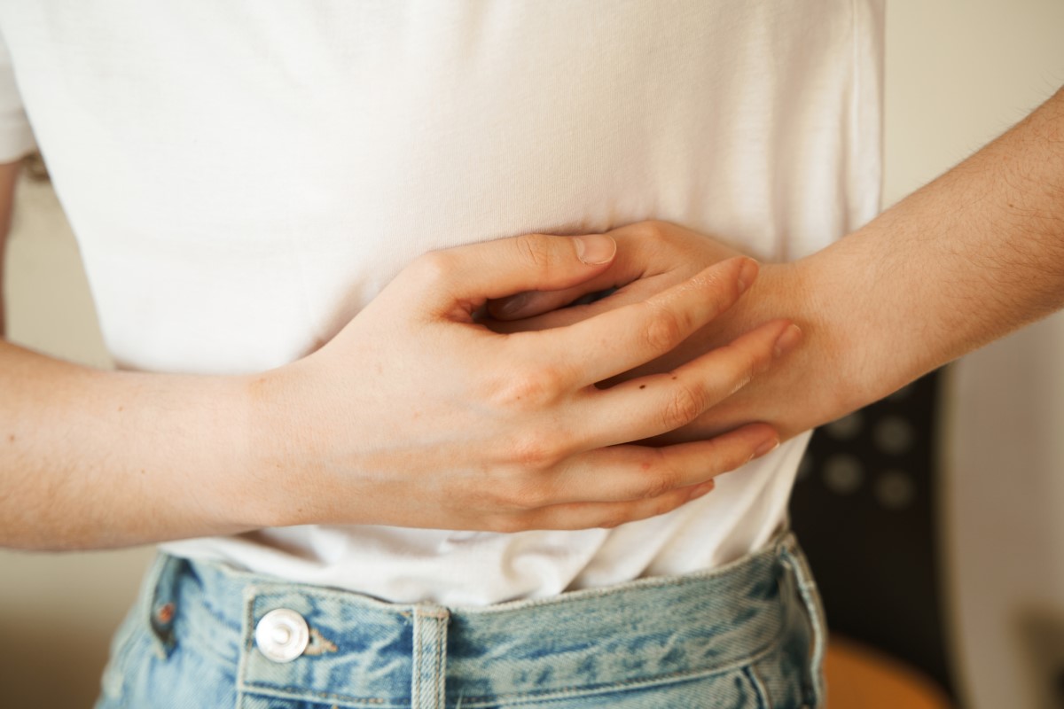 La femme se tient le côté douloureux avec les mains, a des douleurs abdominales et d'autres problèmes de santé qui peuvent indiquer une occlusion intestinale.