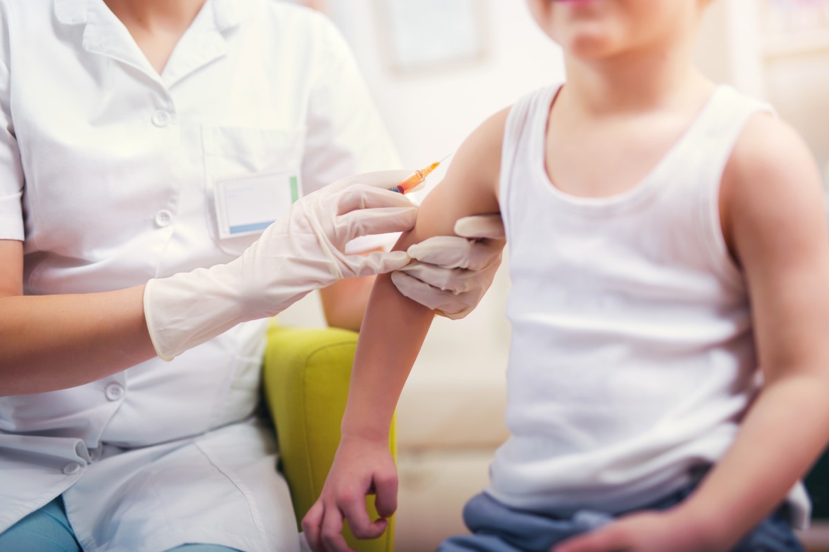 Vaccination d'un enfant - le médecin vaccine l'enfant - l'enfant s'assoit et le médecin lui fait une injection dans le bras.