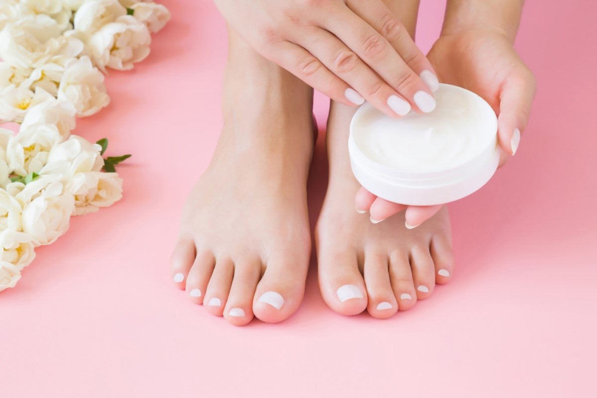 Application de la crème pour les pieds Une femme met de la crème sur ses pieds avec ses mains.