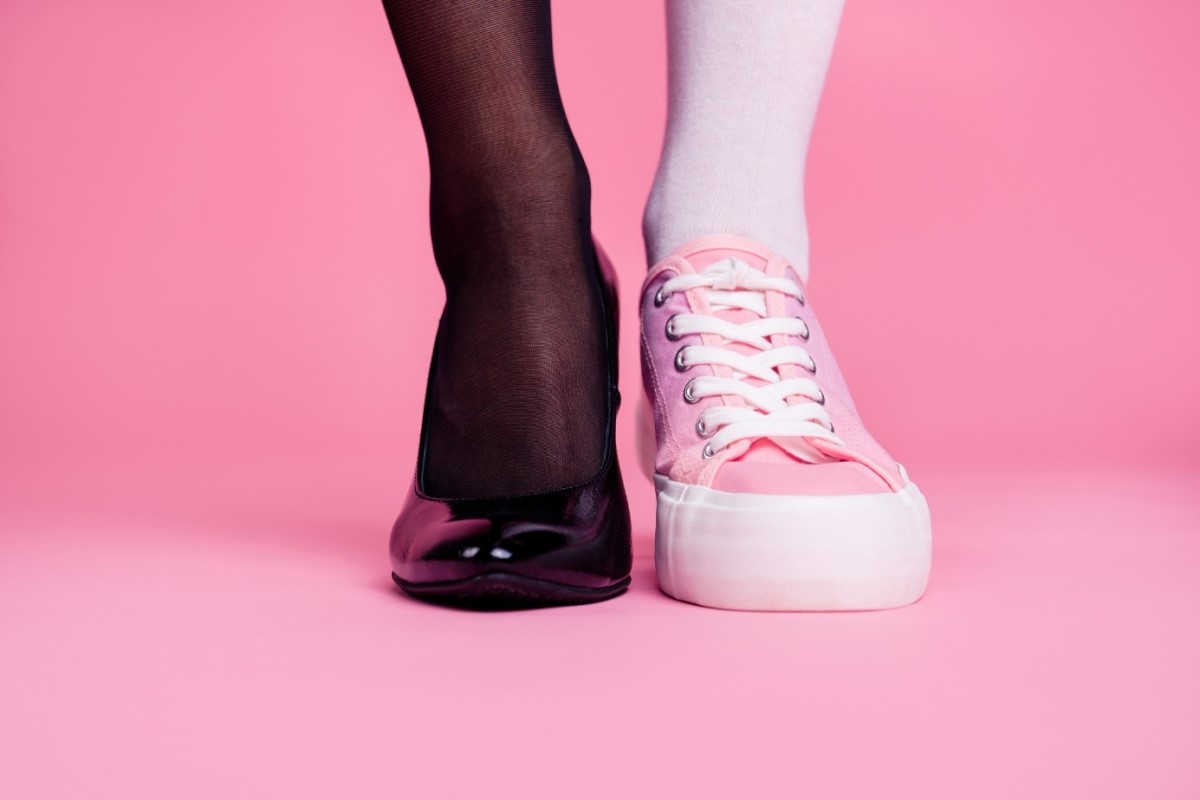 Jambes et chaussures, deux jambes, l'une en bas de soie noirs avec des escarpins noirs et l'autre en bas roses et baskets.