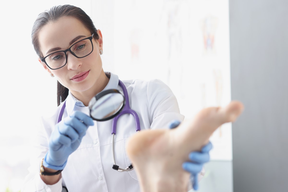 Examen de la peau du pied par un médecin à l'aide d'une loupe.