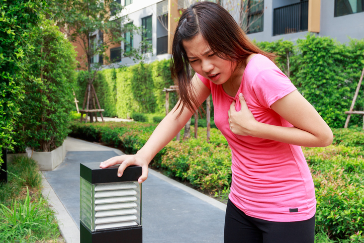 Jeune femme se serrant la poitrine, douleur thoracique, palpitations, palpitations cardiaques