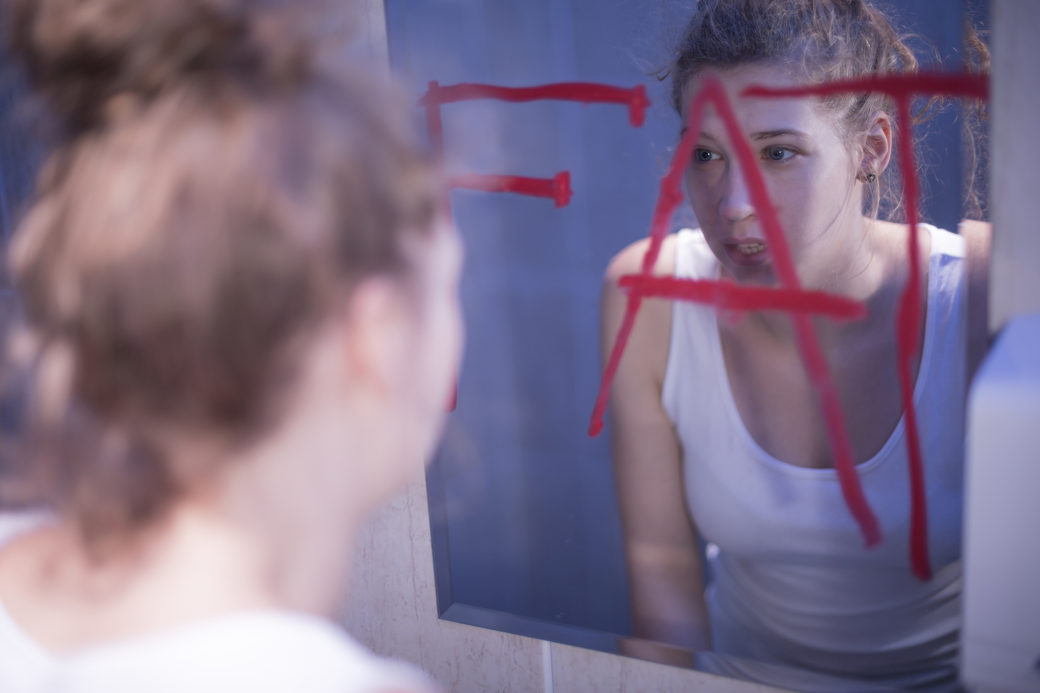 Une jeune femme qui se trouve grosse lorsqu'elle se regarde dans le miroir.