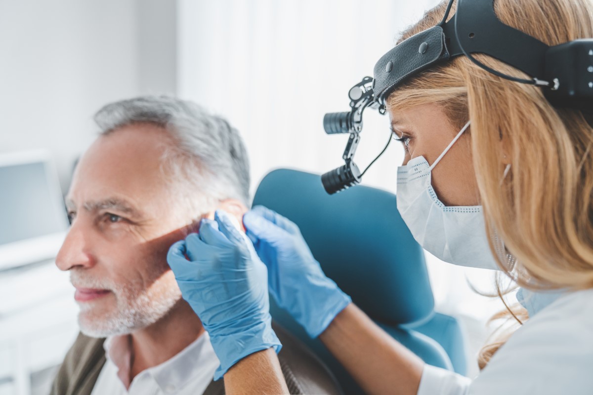 Examen ORL de l'oreille, homme âgé assis sur la chaise d'examen et examiné par un médecin