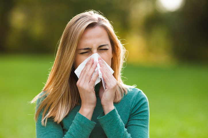 Rhinite allergique non infectieuse, la femme à l'extérieur est enrhumée et éternue.