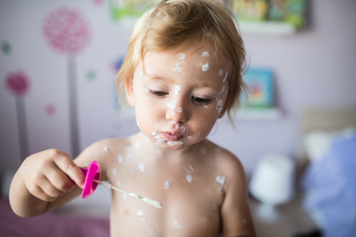 Une petite fille souffre d'un cas bénin de varicelle - elle joue avec un souffleur de bulles.