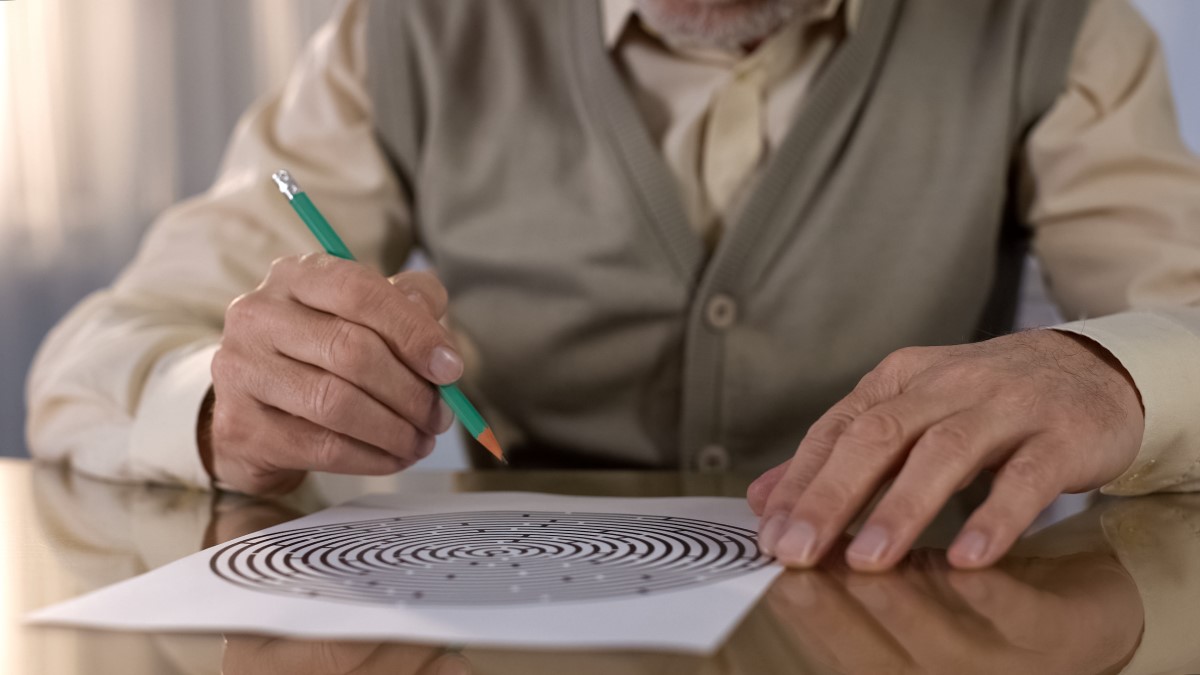 Un senior tente de résoudre un jeu de labyrinthe sur papier