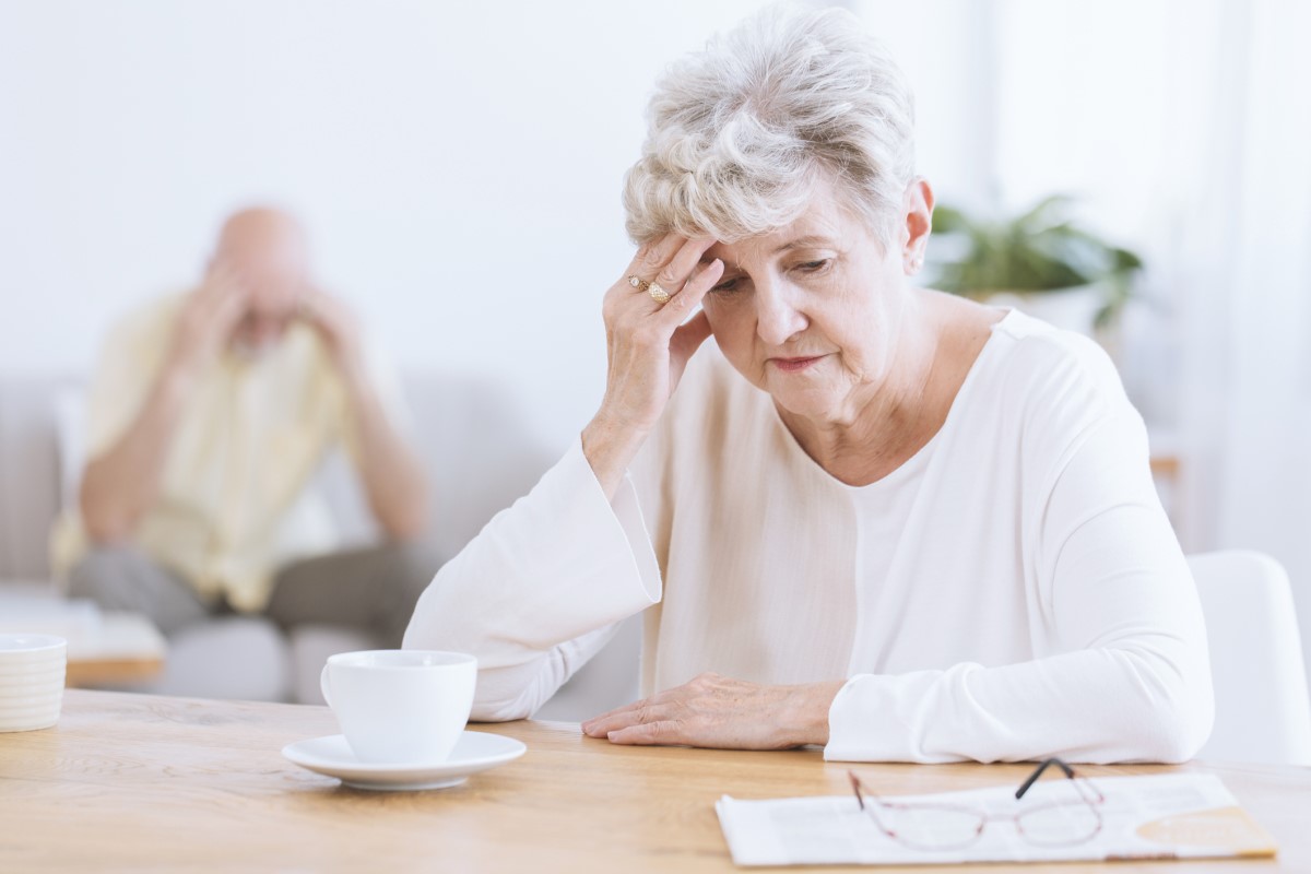 Femme âgée se tenant la tête, en raison de la détérioration des fonctions neurologiques du cerveau, peut-être la maladie d'Alzheimer. Femme âgée au premier plan, tête baissée, s'appuyant sur sa main.