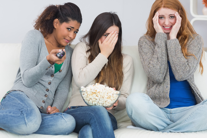 Trois filles ont peur, regardent un film d'horreur, pop-corn dans un bol