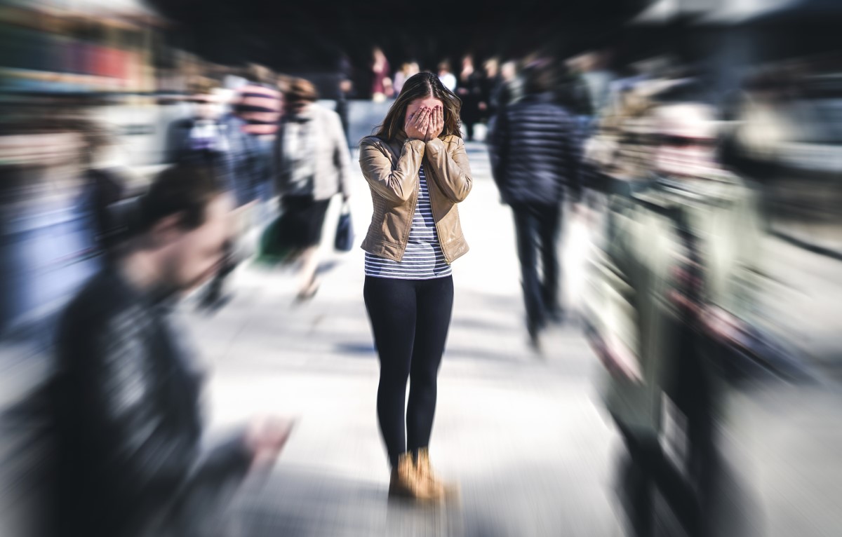 Femme confuse debout dans une foule de personnes, a un problème mental, une sensibilité exagérée à la lumière et aux sons, du bruit