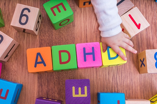 les cubes-lettres de l'enfant, disposés de manière à former le nom ADHD, avec la main de l'enfant