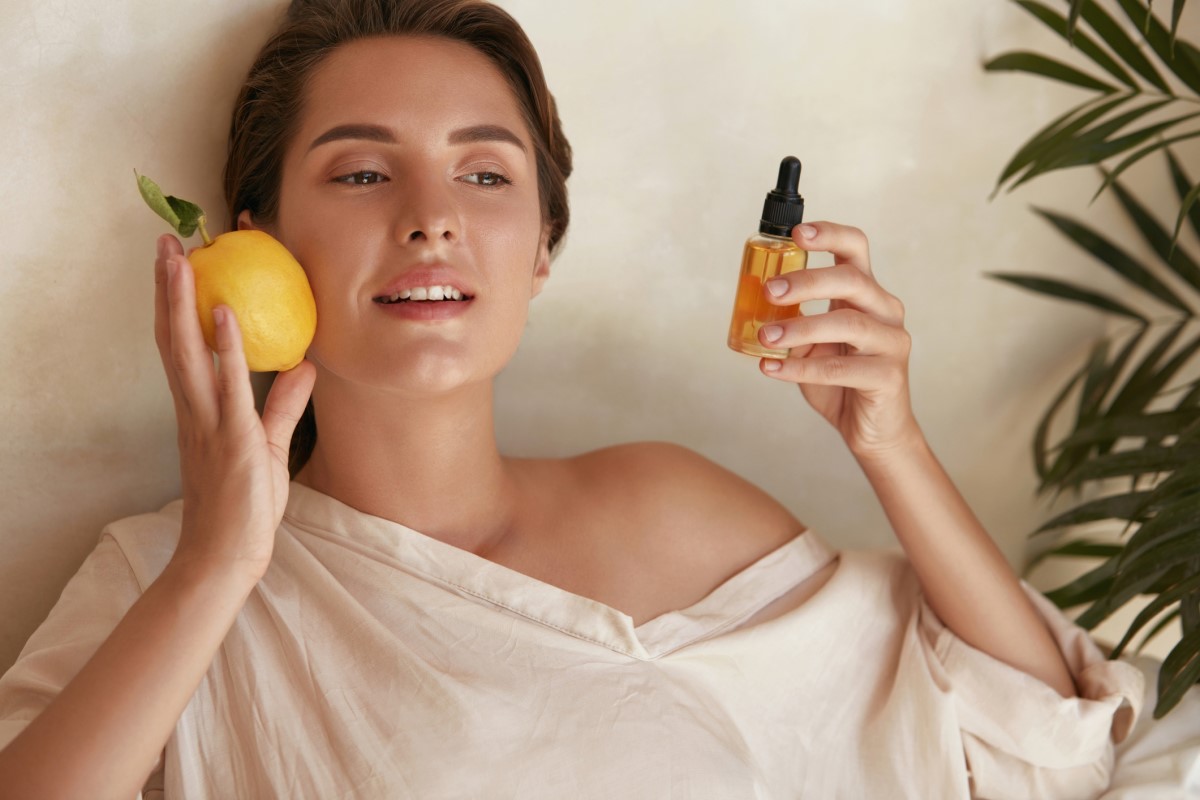 Femme avec un citron et un flacon d'extrait de vitamine C dans la main, une vitamine qui aide la peau