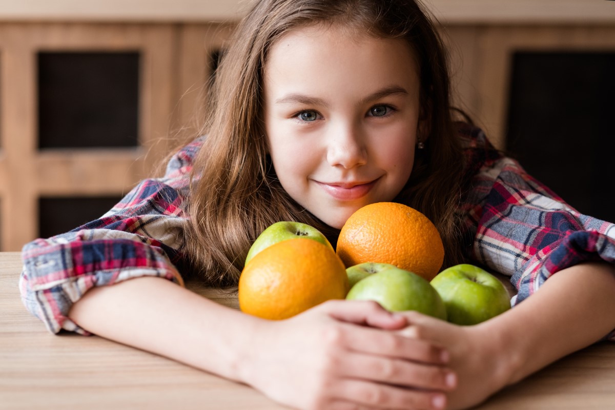 Vitamine C, dans les fruits, un enfant tenant des oranges et des pommes dans ses bras