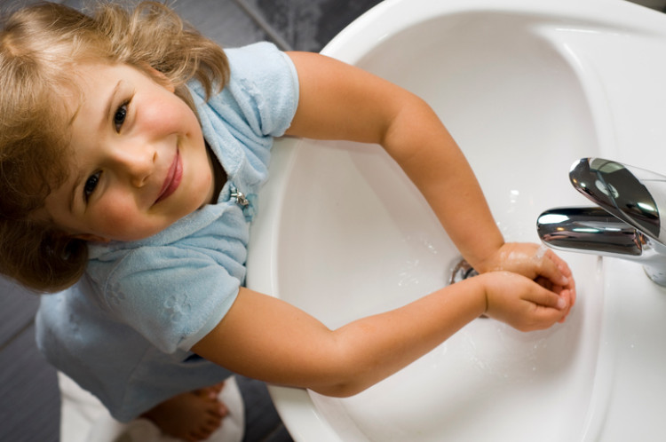 une petite fille se lave les mains avec de l'eau propre provenant de l'évier