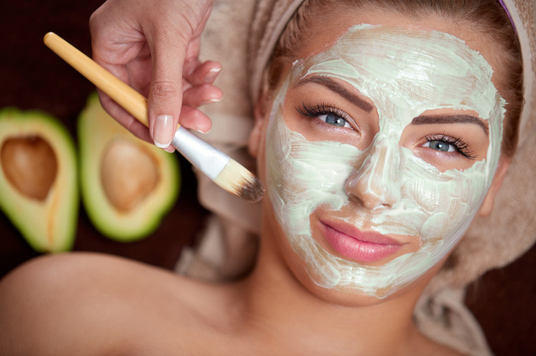 femme avec un turban sur la tête et un masque naturel vert sur le visage, à l'arrière-plan un avocat coupé