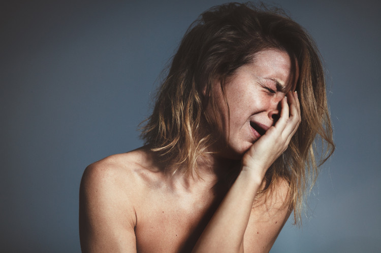 une femme en crise de larmes se tient le visage avec la main