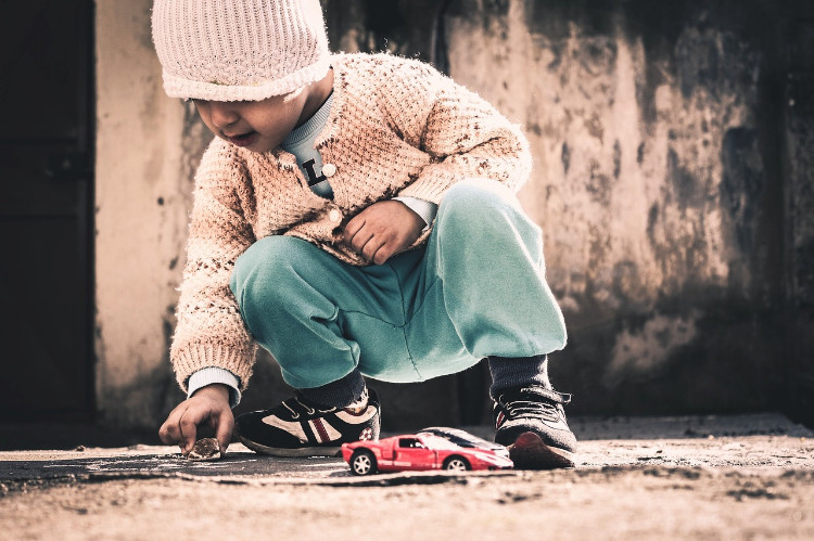 enfant jouant avec une pierre sur le trottoir