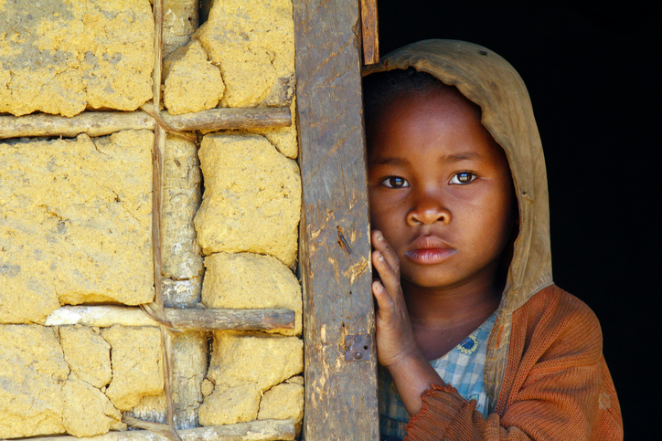 Un pauvre enfant noir au regard triste dans son sweat à capuche appuyé contre le mur.