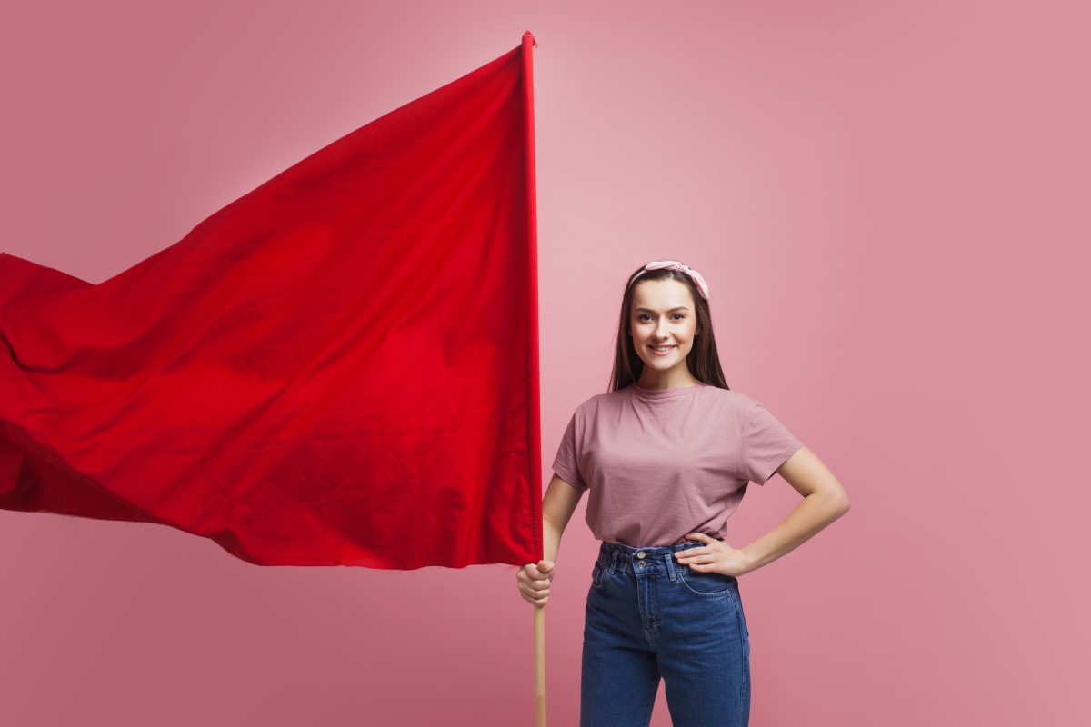 Une femme tient un grand drapeau rouge en guise d'avertissement.