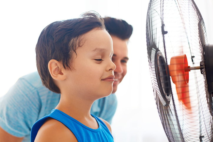 Un garçon et son père devant un ventilateur