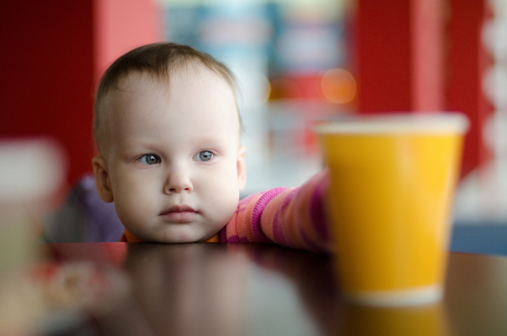 Un petit enfant attrape un verre d'eau sur la table.