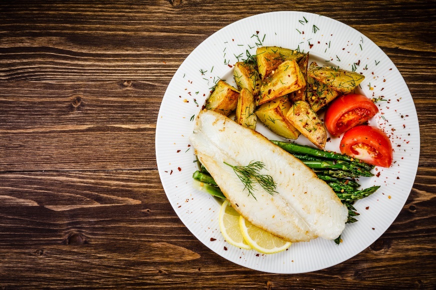 Exemple de dîner : poisson grillé avec asperges, pommes de terre rôties, herbes et légumes frais.