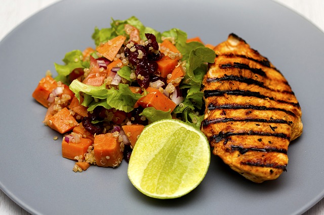 Blanc de poulet grillé, légumes grillés, sur une assiette blanche.