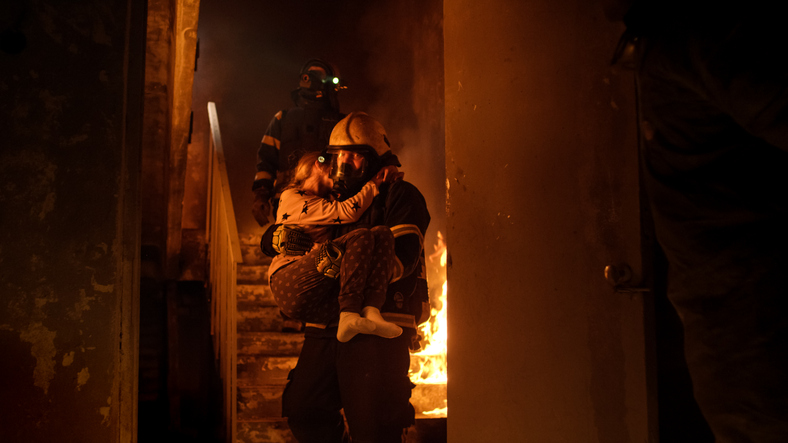 incendie dans la maison, les pompiers sortent l'enfant dans leurs bras