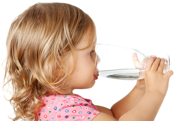 Une petite fille boit de l'eau propre dans un verre