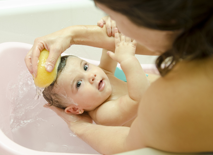 Mère lavant son bébé dans un bain d'éponge