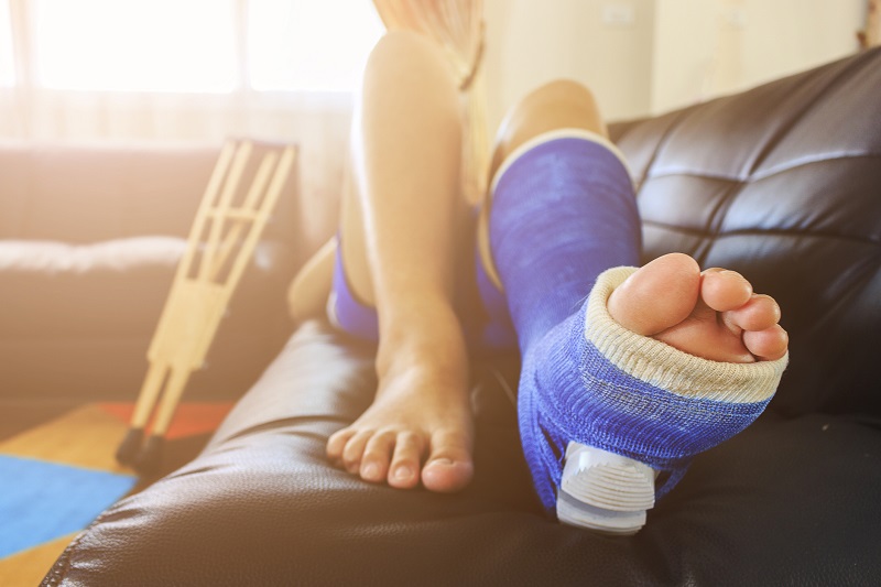 Un homme au lit avec un appareil orthopédique et des béquilles.