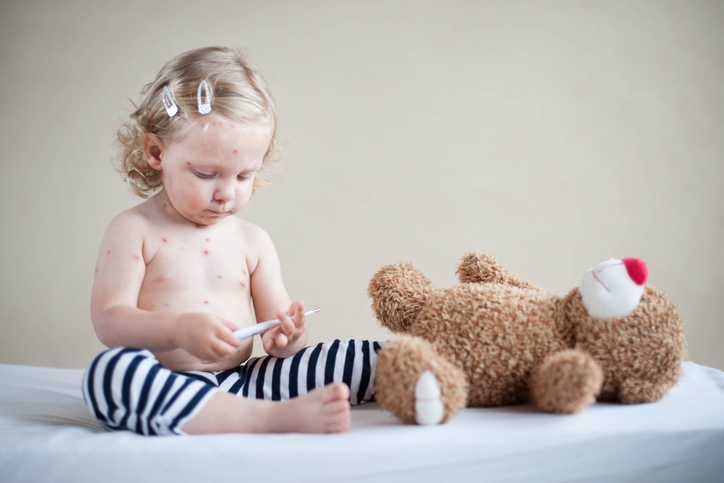 un enfant atteint de rougeole joue avec un ours en peluche