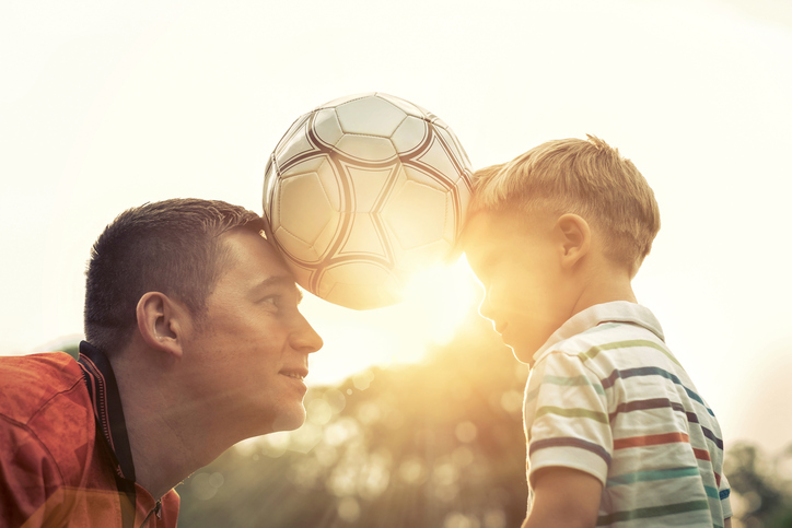 Le père et le fils tiennent le ballon entre eux.