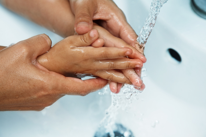 les mains de la mère au-dessus de l'évier laver les mains du bébé à l'eau courante