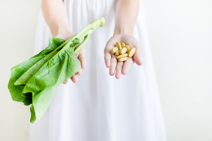 Mains tenant des pilules et des feuilles de salade