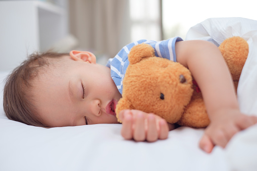 Enfant en bas âge dormant avec un ours en peluche