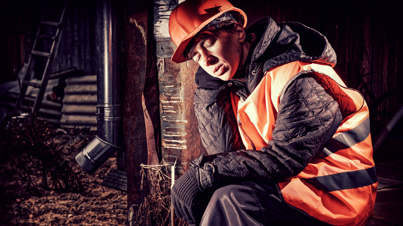 Homme endormi au travail avec un casque rouge et un gilet réfléchissant