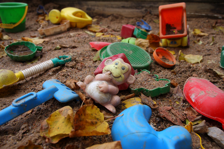 De vieux jouets dans un bac à sable pollué