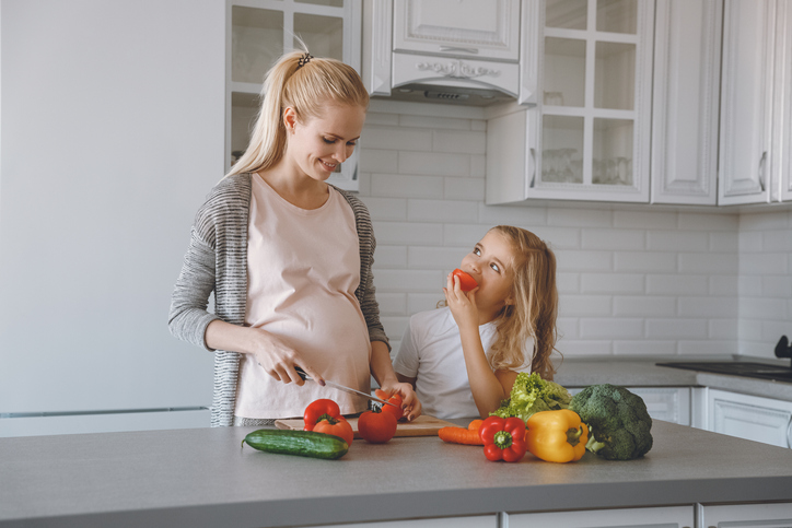 Une mère enceinte et sa fille préparent un repas sain dans la cuisine.