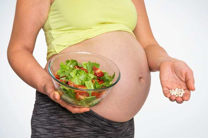 Femme enceinte avec salade et pilules