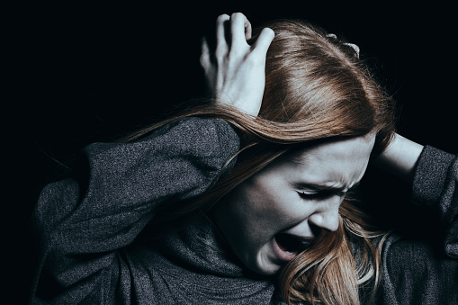 la femme se tient les cheveux et crie, elle est agressive