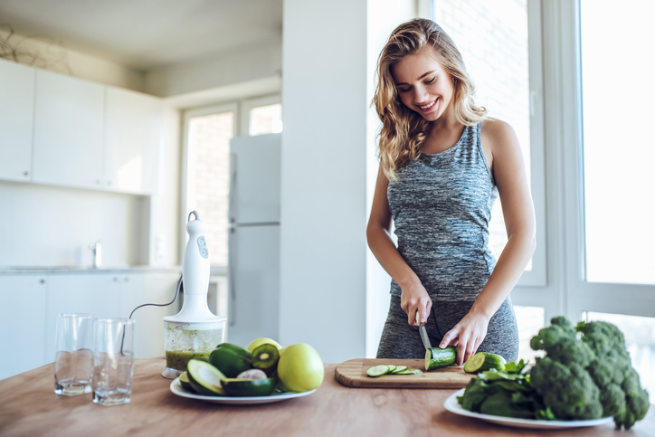 Une jeune femme coupe des légumes dans la cuisine.