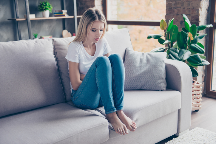 la femme souffre, assise sur le canapé 