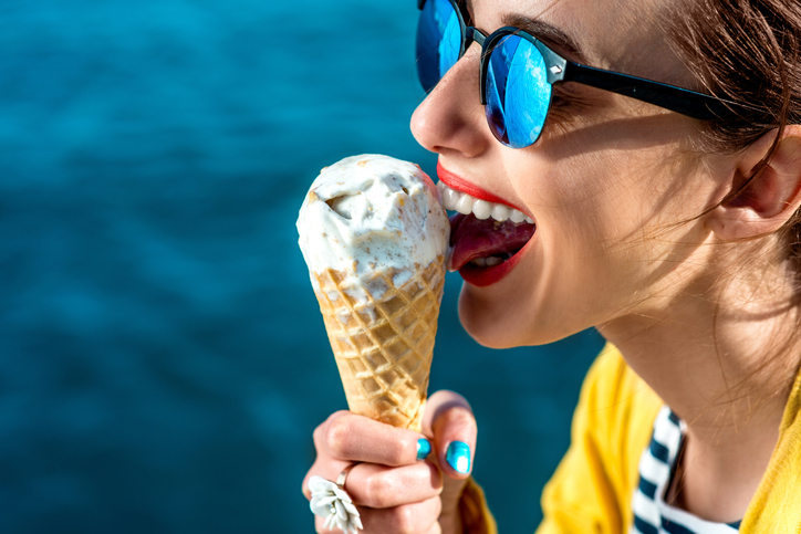 femme avec lunettes de soleil léchant une glace au bord de l'eau