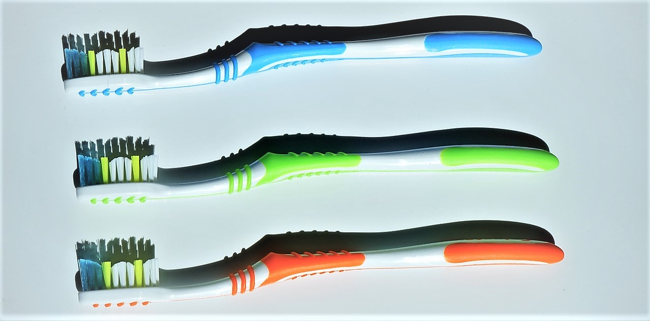 Brosses à dents, variantes de couleurs, trois pièces, bleu en haut, vert au milieu, orange en bas, poils colorés sur la tête de la brosse à dents, bleu, vert et blanc