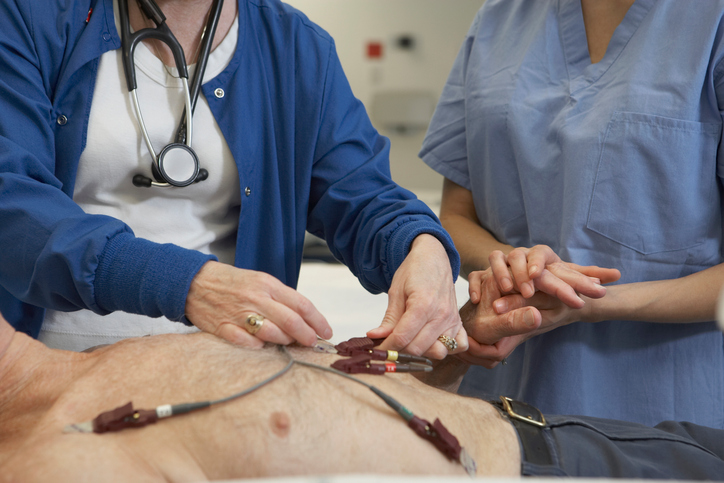 Examen électrocardiographique de l'homme, électrodes sur sa poitrine, deux médecins l'examinent