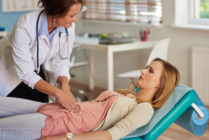 Un médecin examine une femme souffrant de douleurs abdominales.