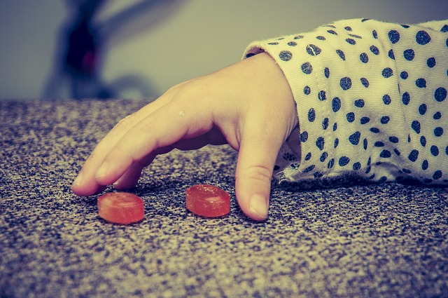 Une main d'enfant, deux bonbons rouges, de mauvaises habitudes alimentaires