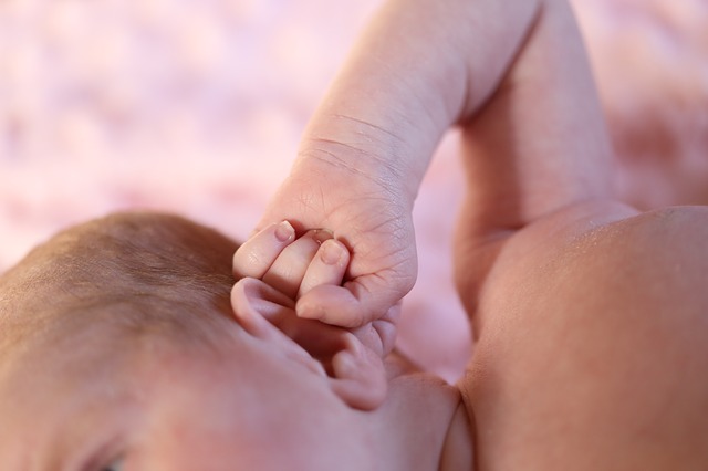 un petit enfant (bambin) se tient l'oreille avec sa main