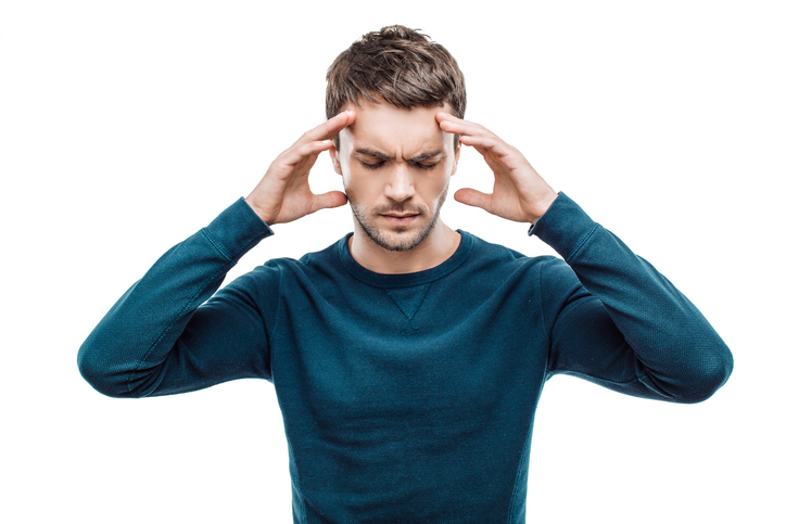 L'homme a mal à la tête et se tient les tempes avec les mains.